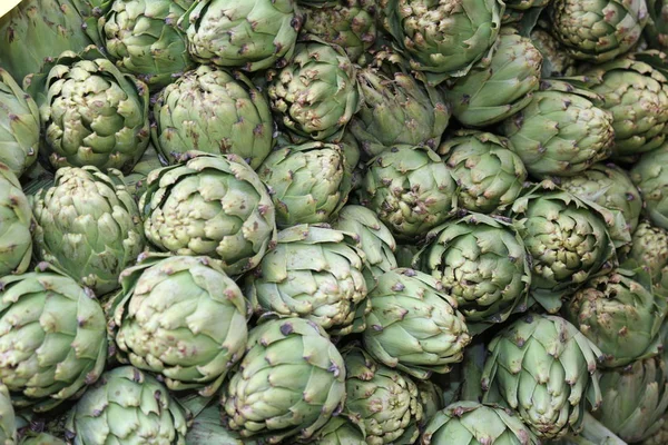 Green background of artichokes for sale — Stock Photo, Image
