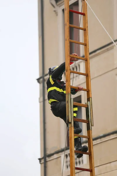 Fireman climbs above the staircase — Stock Photo, Image