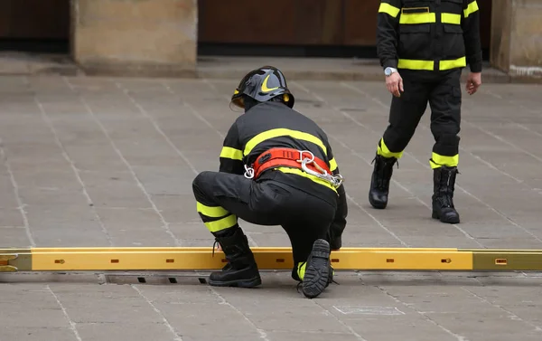 Firemen during rescue operations with a wooden ladder — Stock Photo, Image