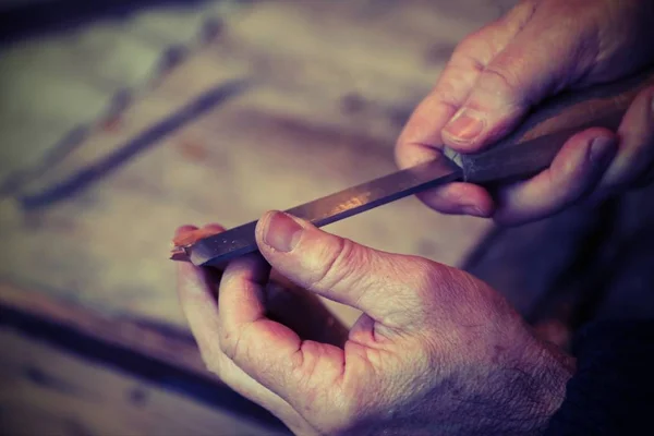 Manos de un carpintero anciano mientras que el pedazo de madera con un chi —  Fotos de Stock