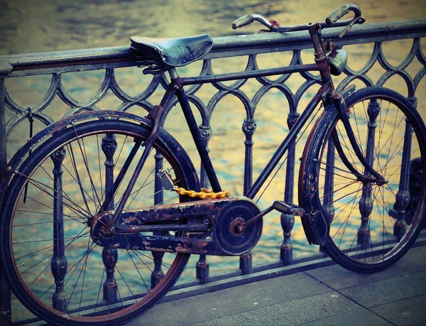 川の上の橋の上に傾いている黒の古い自転車 — ストック写真