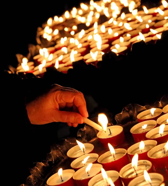 Muitas velas acesas na igreja e na mão da senhora — Fotografia de Stock