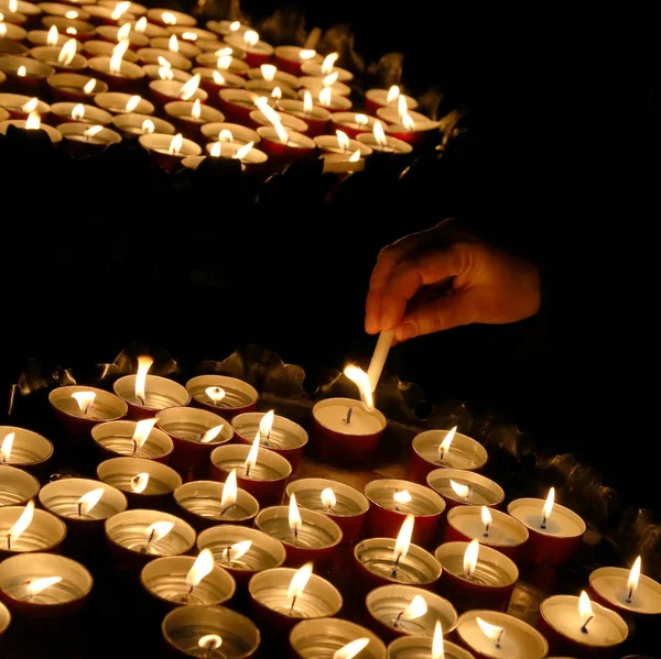 Mãos de uma mulher idosa que acende uma vela durante a Santa Mãe — Fotografia de Stock