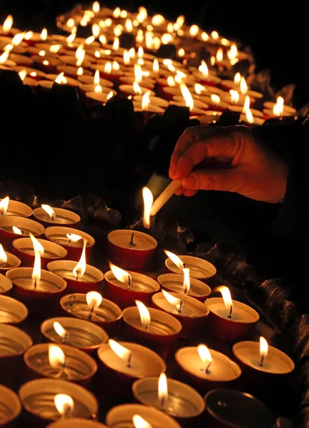 Viele Kerzen in der Kirche entzündet und die Hand der alten Dame — Stockfoto