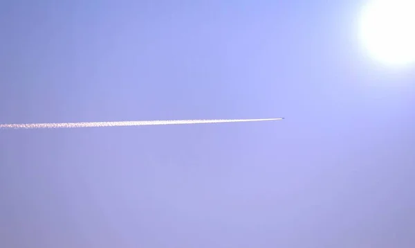 Vliegtuig met witte rook trail vliegen naar de zon — Stockfoto