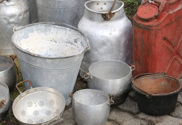 Old aluminum containers and an ancient red tank to transport the — Stock Photo, Image