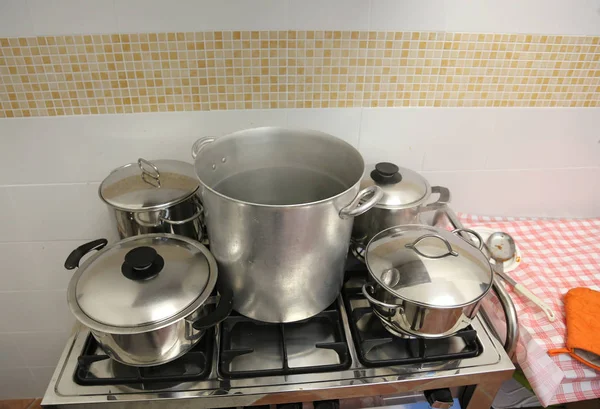 Muchas ollas de acero grandes y una cacerola pequeña en la estufa dentro de la — Foto de Stock