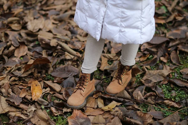 Winter leather boots of a little girl on the dry autumn leaves — Stock Photo, Image