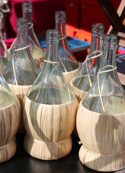 Many flasks for holding wine with straw coating — Stock Photo, Image