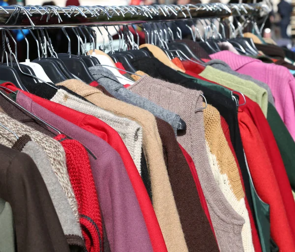 Camisolas penduradas em cabides para venda no mercado — Fotografia de Stock