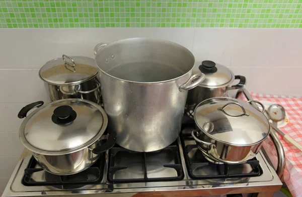 Large and small pots in the industrial kitchen on the stove — Stock Photo, Image