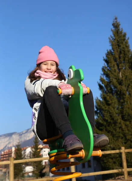 Pretty little girl playing on the carousel of a playground — Stock Photo, Image