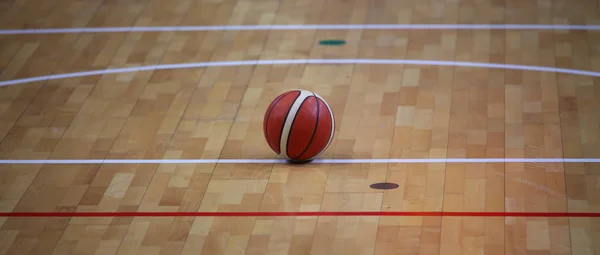 Bola de basquete na quadra de basquete com um parquete de madeira — Fotografia de Stock