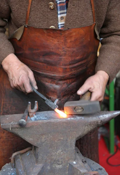 Hände eines älteren Schmieds, der Eisen mit einem Hammer bearbeitet und — Stockfoto