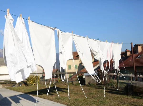 Lavati grembiuli bianchi si asciugano al sole caldo in un villaggio — Foto Stock