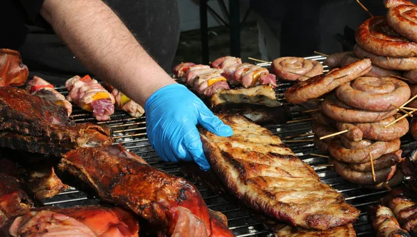 Koken met blauwe handschoenen besturingselementen het koken van gegrilde tussenribstuk — Stockfoto