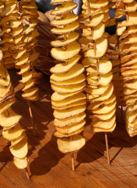 Batatas fritas em fatias e amarrados no espeto de madeira na rua — Fotografia de Stock