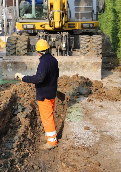 Werknemer in de gracht en de grote bulldozer in de bouw-s — Stockfoto