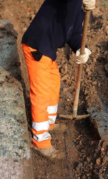 Работник с лопатой внутри в траншее в дорожных работах — стоковое фото
