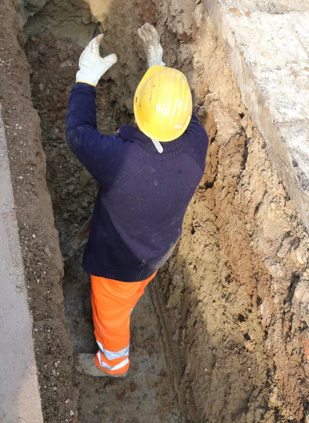 Mann bei der Arbeit mit gelbem Hut im Schützengraben — Stockfoto