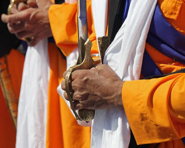 Homens com vestido laranja e uma espada — Fotografia de Stock