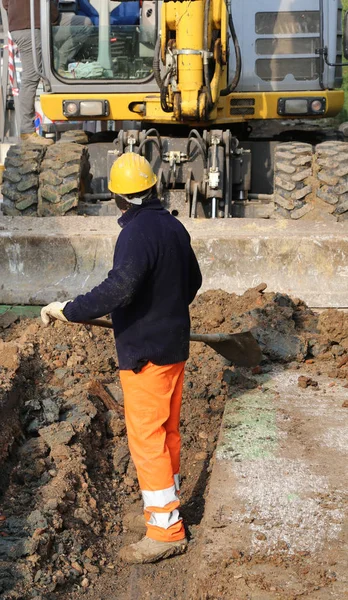 Hombre en el trabajo y la gran excavadora en la carretera —  Fotos de Stock