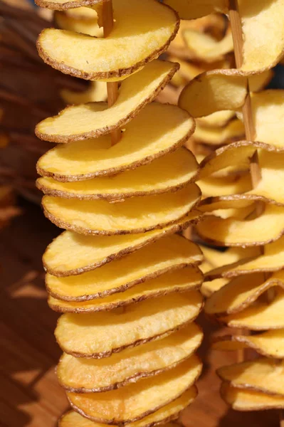 Жареный нарезанный картофель застрял в деревянном шампуре на улице — стоковое фото