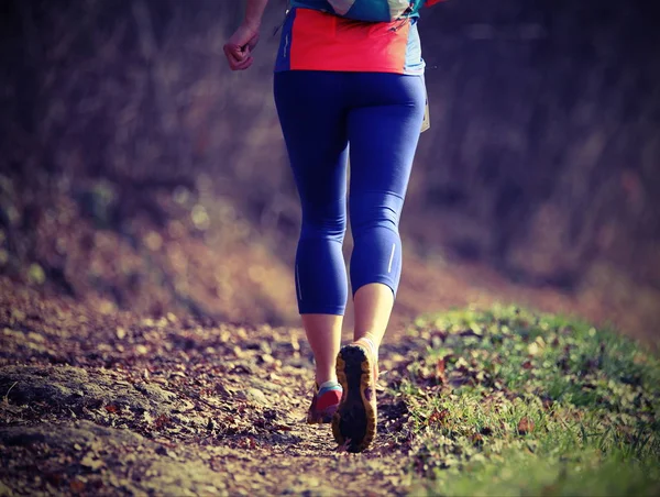 Женщина быстро бегает в спортивном костюме по горной тропе во время — стоковое фото