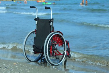 Güneşli bir deniz kıyısında tekerlekli sandalye
