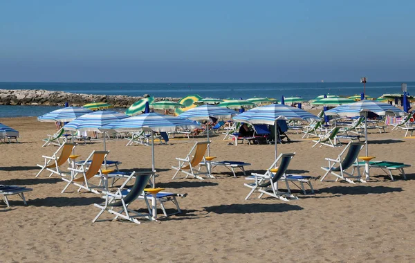 Beach umbrellas and sunbeds on the sand of the tourist village b — Stock Photo, Image