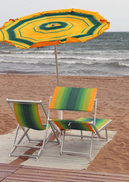 Sonnenschirme und Liegen am Strand an einem windigen Tag — Stockfoto