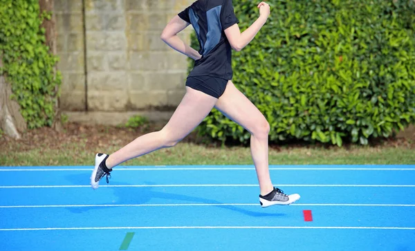 Chica joven corre en la pista de atletismo durante el entrenamiento deportivo —  Fotos de Stock