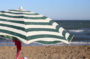 Large sun parasol on the shore of the ocean in the hot summer su clipart