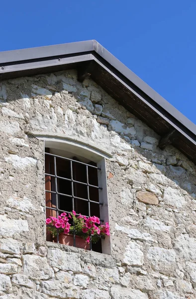 Flores rosas en primavera en el balcón de una casa de piedra — Foto de Stock