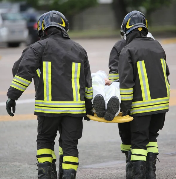 Cuatro valientes bomberos transportan a los heridos con una camilla —  Fotos de Stock