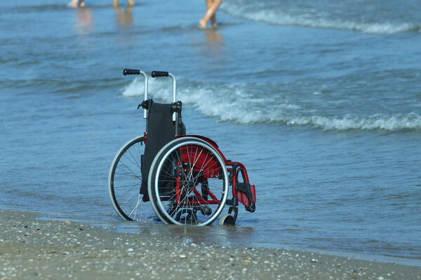 Wheelchair on the shore by the sea on a hot sunny summer day