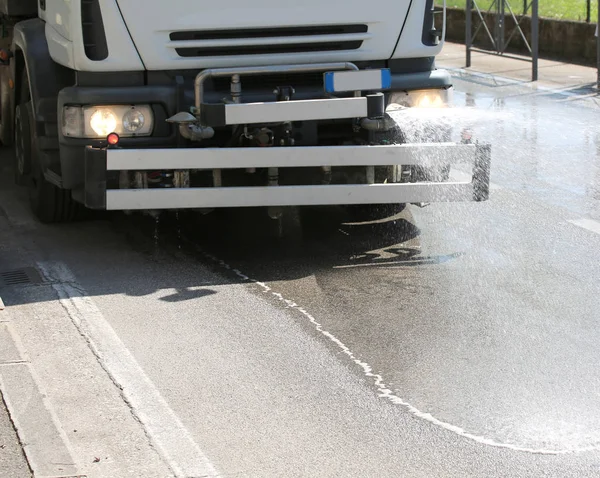 Water splash van vrachtwagen voor het wassen van de stedelijke wegen — Stockfoto