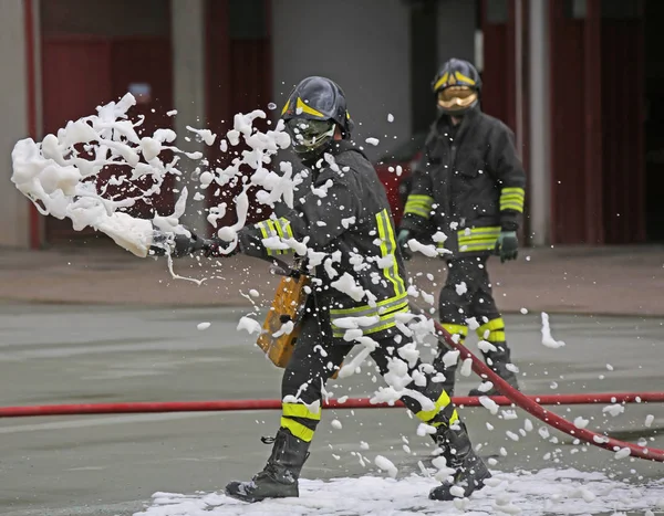 Firefighters while extinguishing the fire with foam — Stock Photo, Image