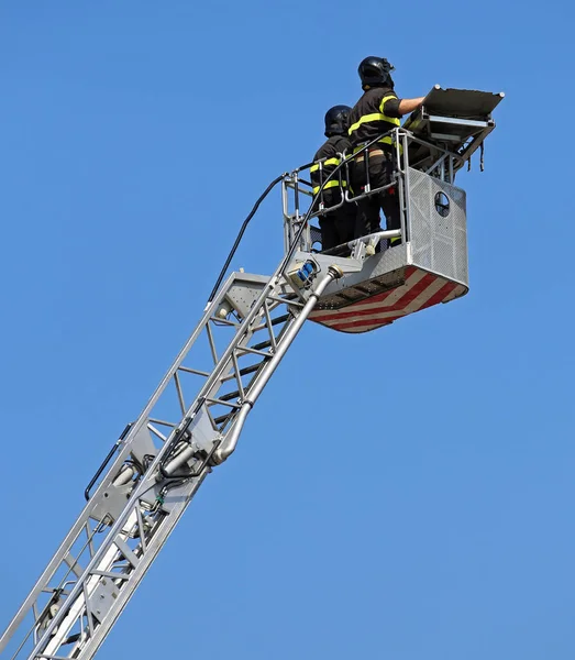 Two intrepid firefighters over the ladder truck metal basket — Stock Photo, Image