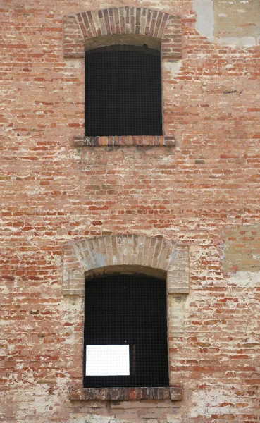 Due finestre di un vecchio edificio in mattoni con griglie in ferro — Foto Stock