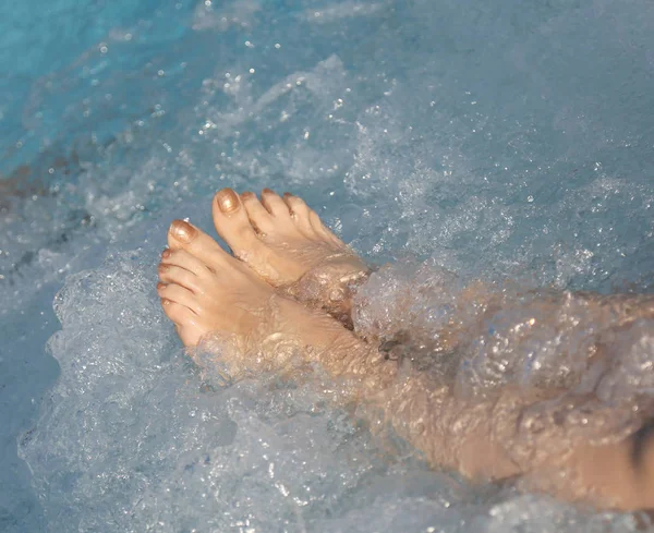 Frau im Wellness-Pool und Whirlpool zu ihren Füßen mit Nägeln mit Emaille — Stockfoto