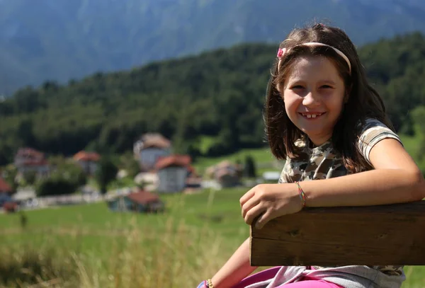 Dość kaukaski dziewczynka z długie brązowe włosy uśmiechając się na ben — Zdjęcie stockowe