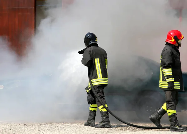 Tűzoltók védő egységes és a sisak le a tüzet a — Stock Fotó