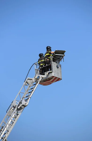 Dos intrépidos bomberos sobre la canasta metálica de autoescala durante —  Fotos de Stock