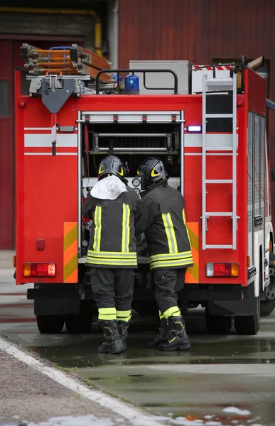 Feuerwehrleute und das Löschfahrzeug während eines Einsatzes — Stockfoto