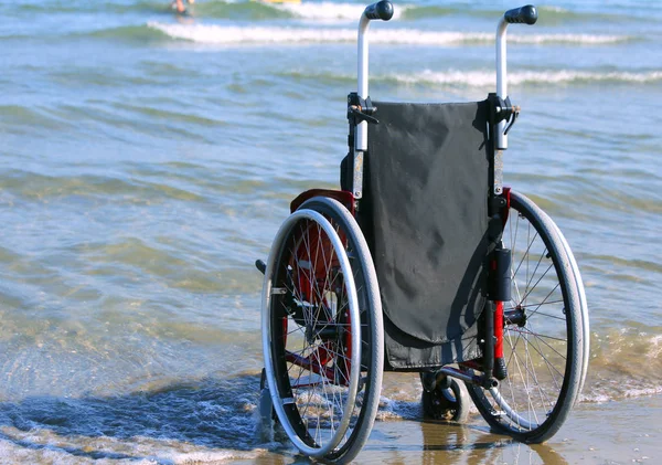 Wózek inwalidzki na brzegu morza na gorący słoneczny letni dzień — Zdjęcie stockowe