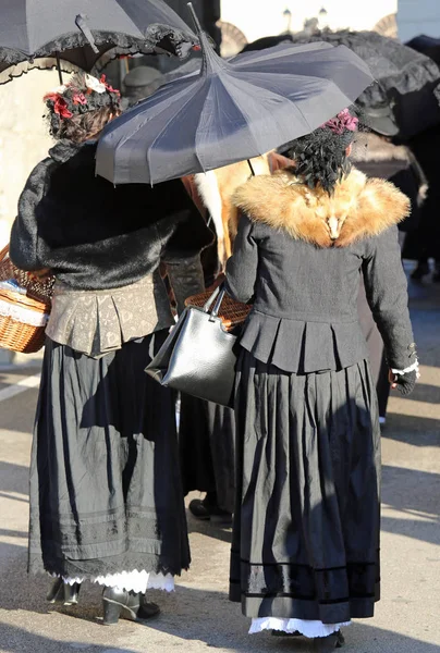 Mulheres vestidas com roupas vintage e um guarda-chuva preto para proteger — Fotografia de Stock