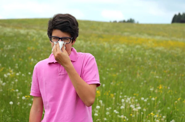 Allergic boy with glasses and pink t-shirt blows his nose — Stock Photo, Image