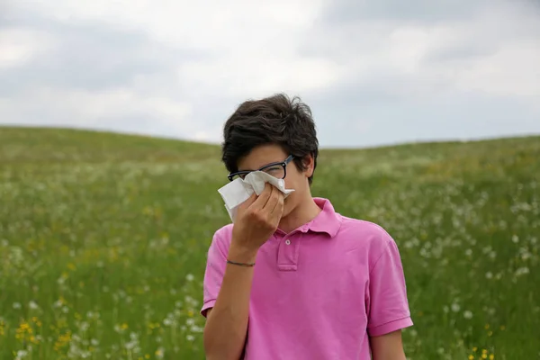 Jongen met allergie en roze t-shirt blaast zijn neus met behulp van een handker — Stockfoto