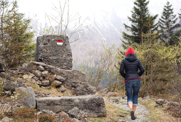 Giovane donna con cappuccio rosso cammina sul sentiero di montagna — Foto Stock